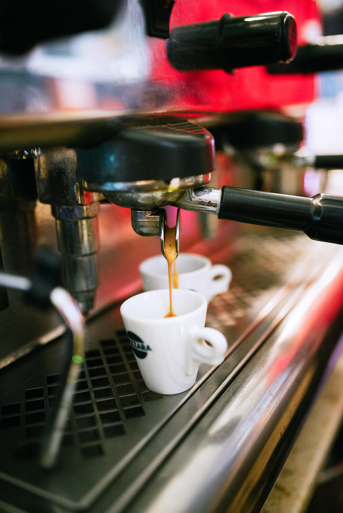 Café espresso sirviéndose desde una máquina a dos tazas pequeñas